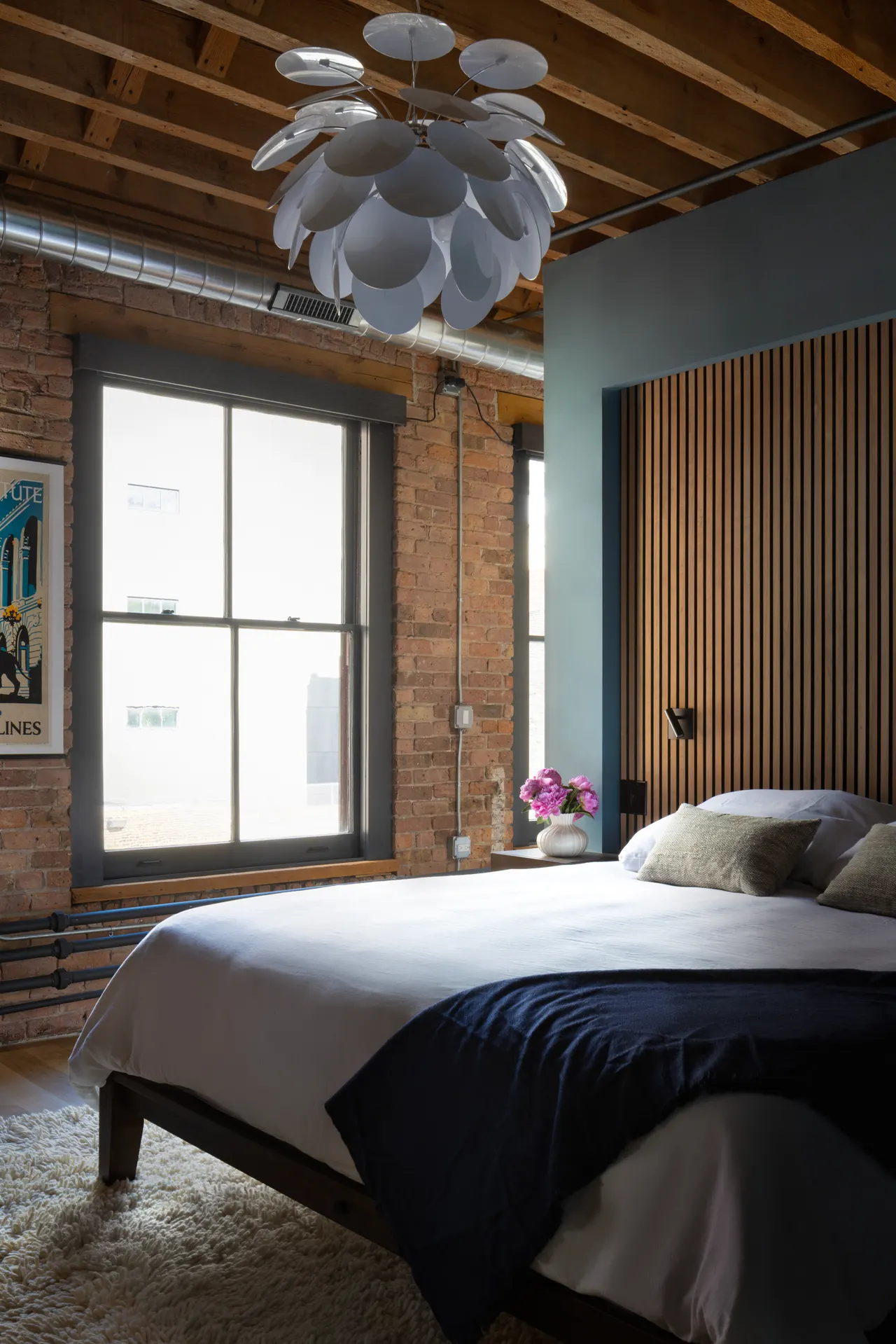 Bedroom with sculptural pendant and factory window