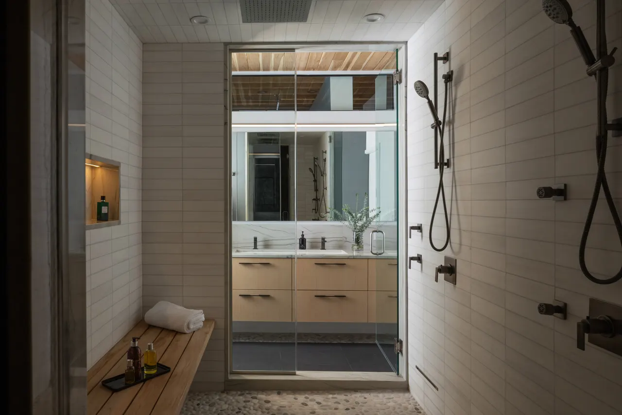 Bathroom with wood shower bench and view to the vanity