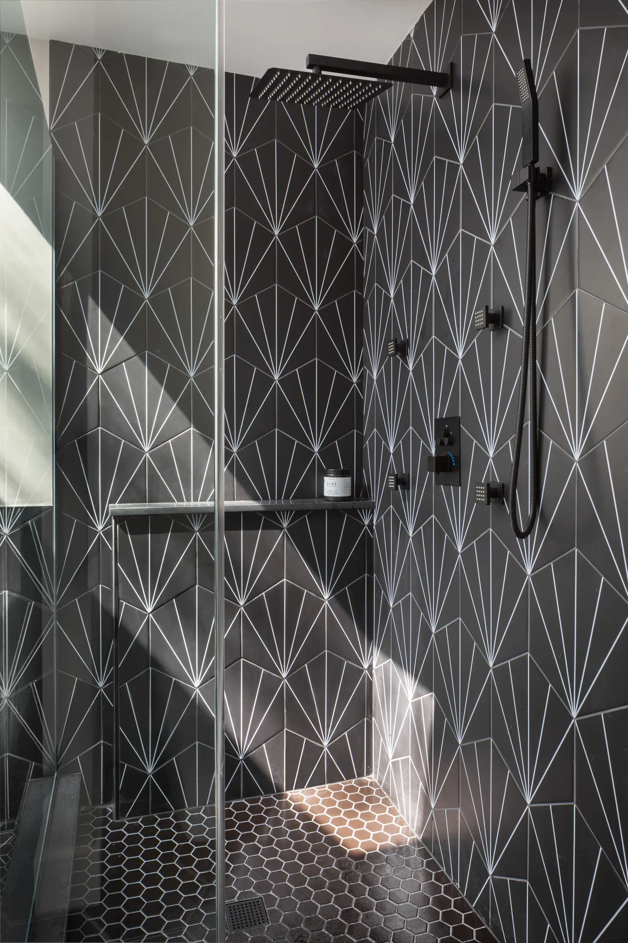 Walk-in shower clad in black fan-pattern tile