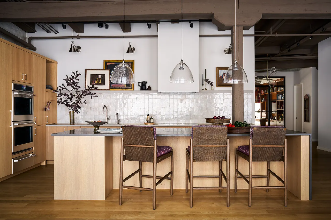 Open kitchen with light wood cabinetry, glossy tile backsplash and island seating