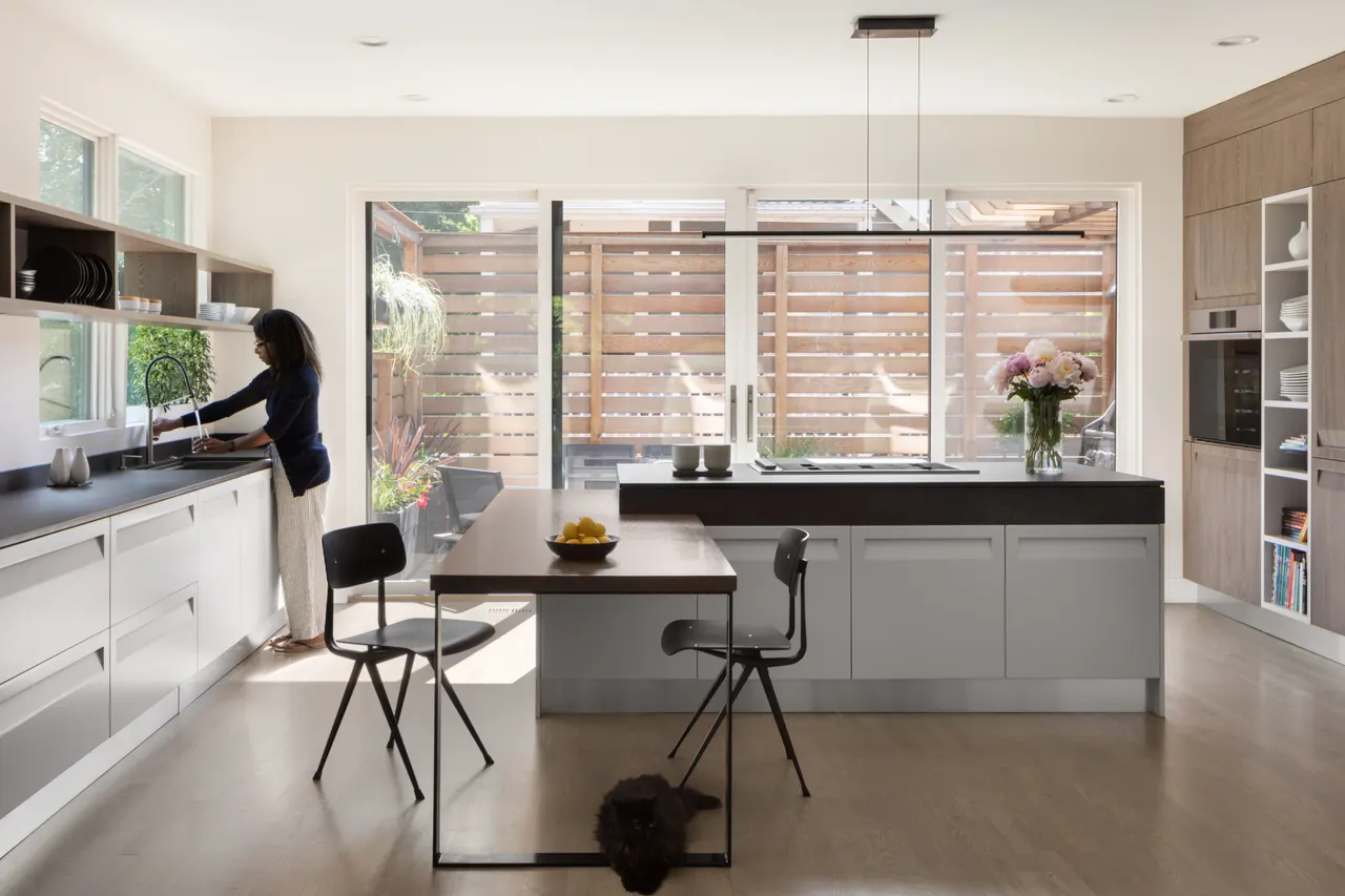 Open kitchen with white cabinetry, wood table and garden views
