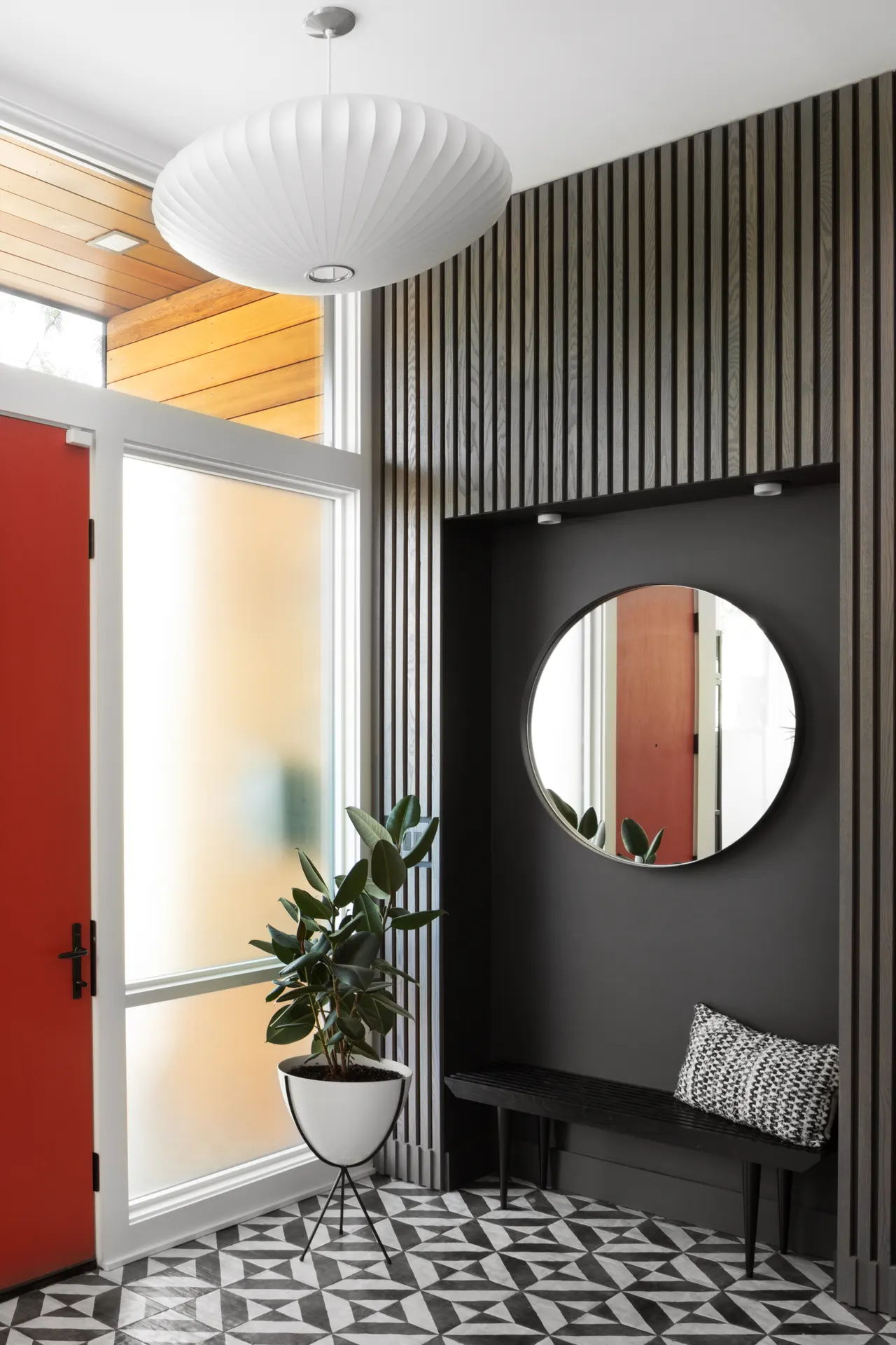 Entry detail: slatted wall, round mirror and red door