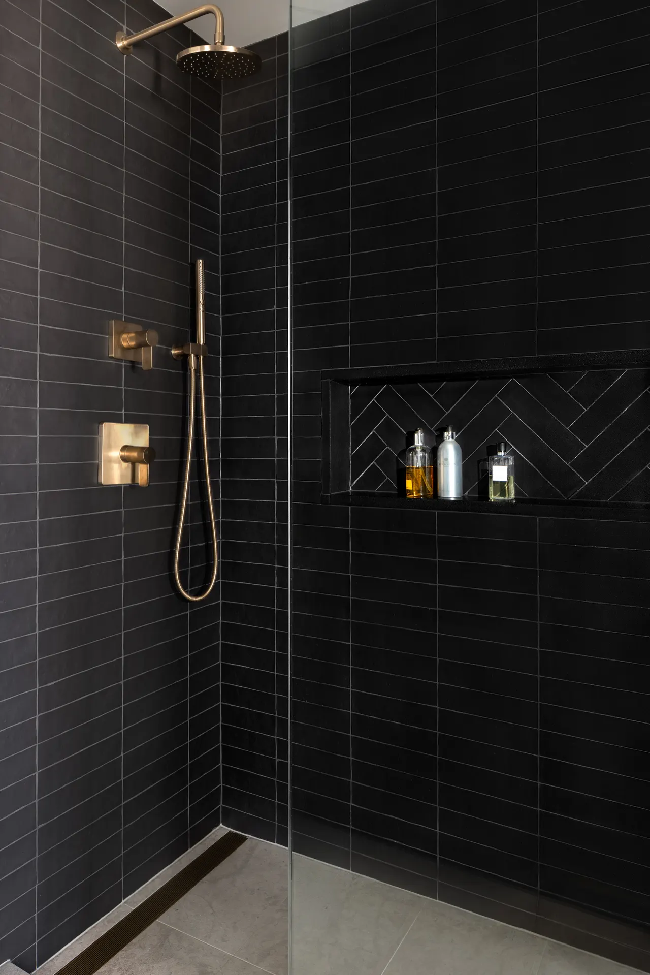 Shower with black tile and brass fixtures