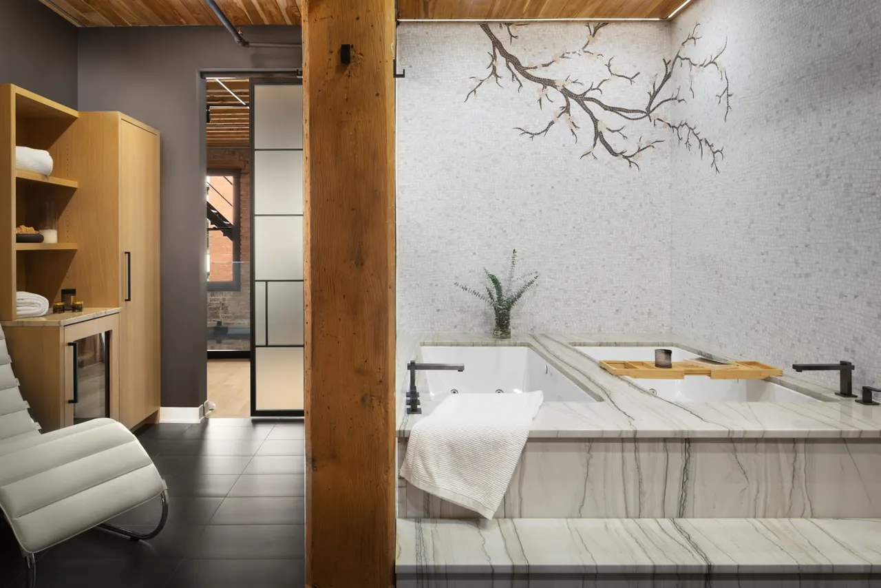 Soaking tub against a stone wall with a branch motif