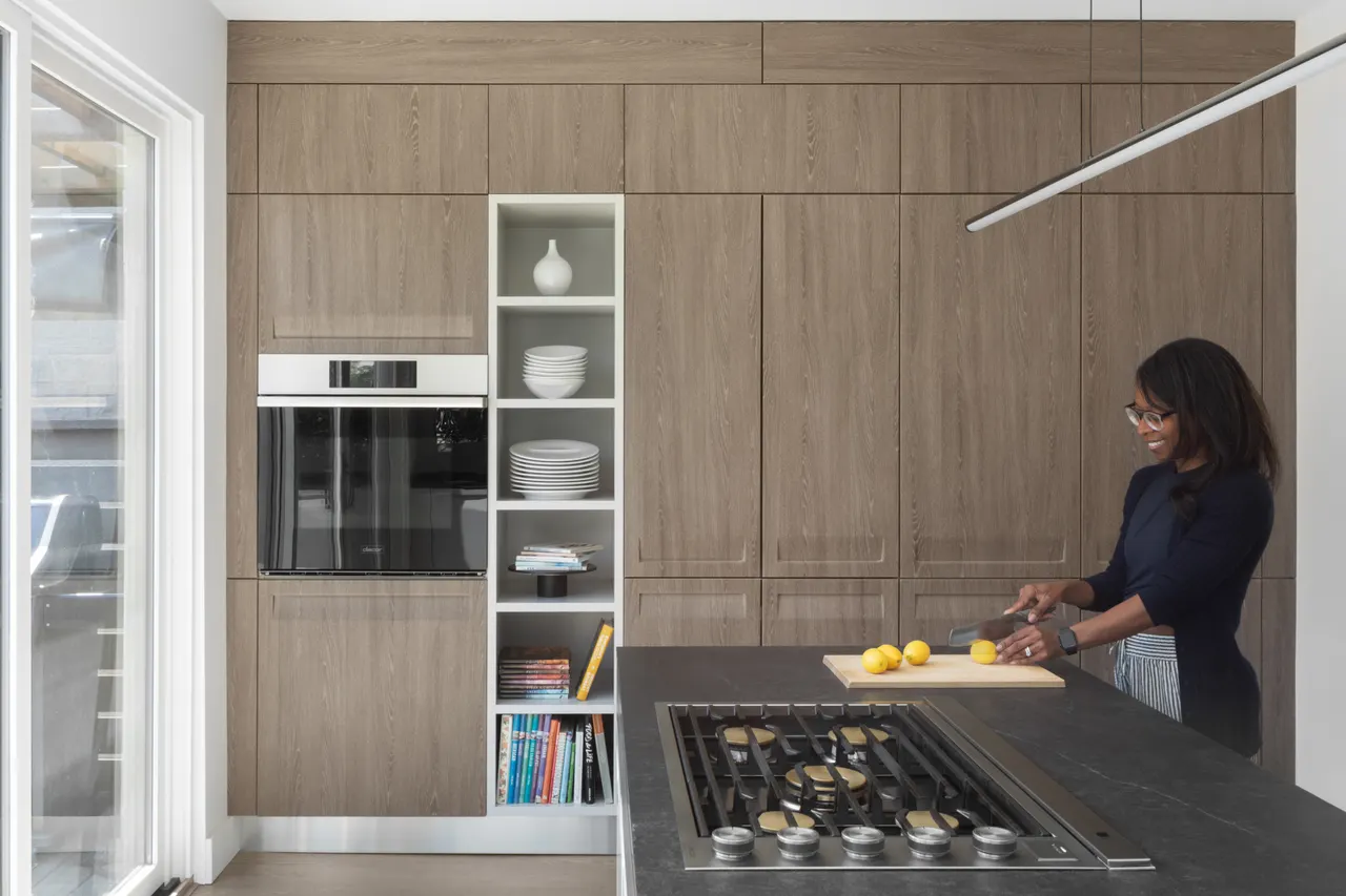 Wood-grain tall cabinet wall with built-in ovens and cooktop island