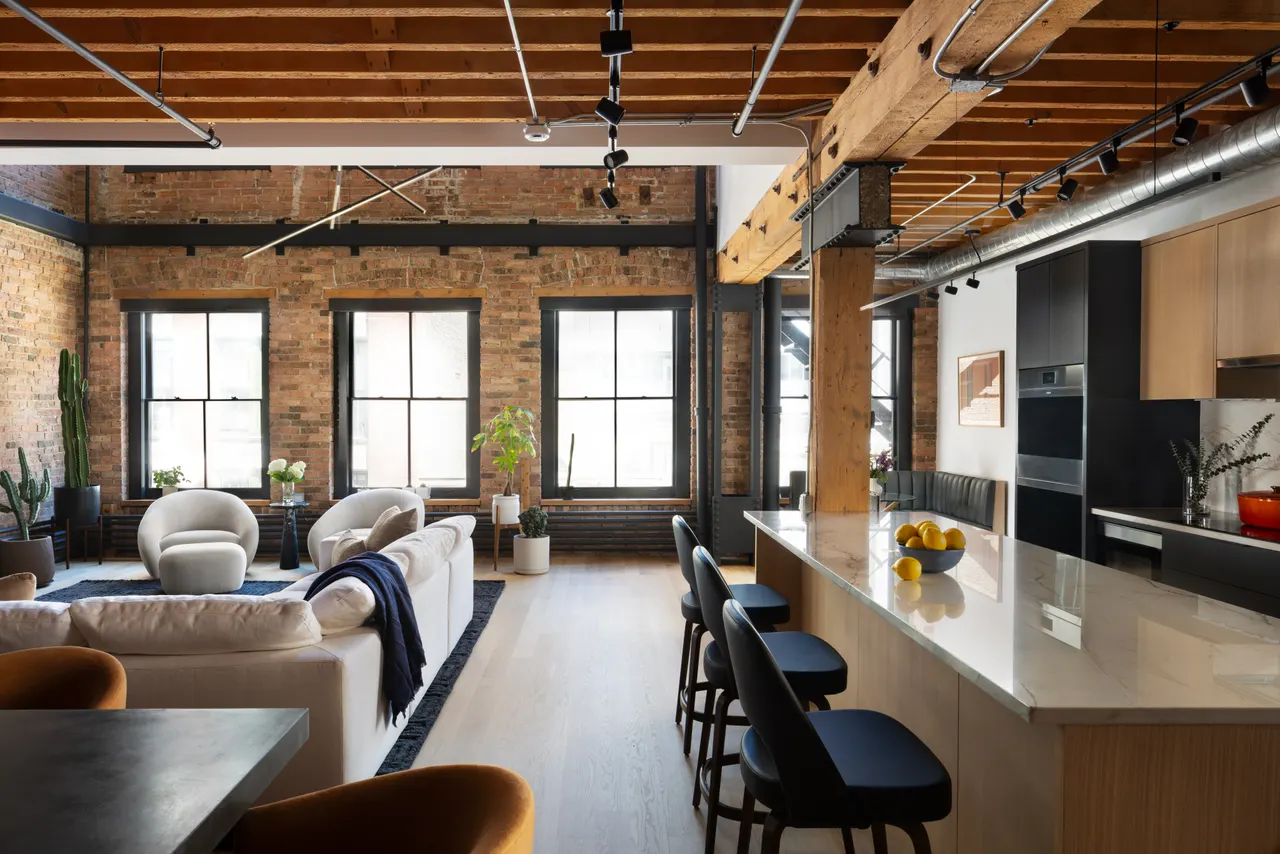 Open living room and kitchen along the brick wall and windows
